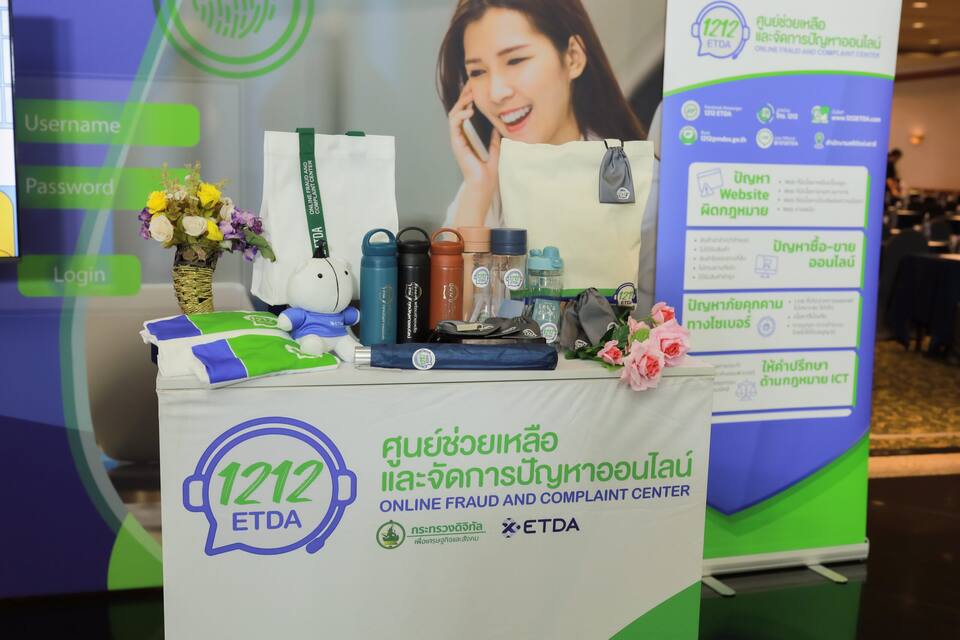 โต๊ะจัดแสดงสีเขียว วางแผ่นพับ ขวดน้ำ และของที่ระลึก