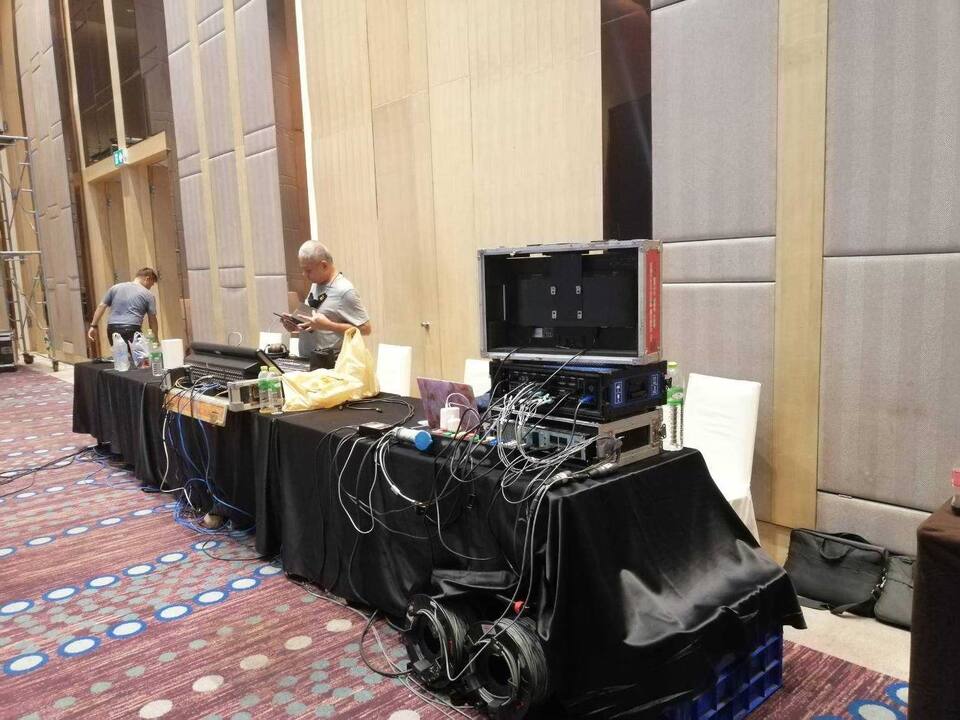 ทีมช่างติดตั้งอุปกรณ์ภาพและเสียงบนโต๊ะในห้องจัดเลี้ยง