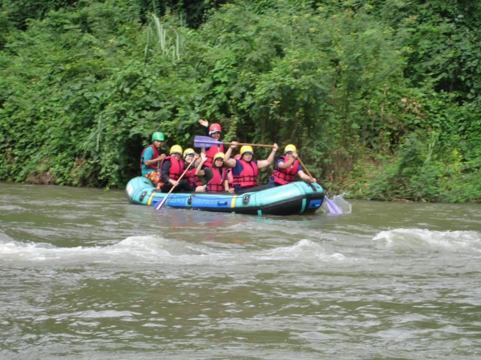 ทีมพนักงานสวมหมวกกันน็อกและเสื้อชูชีพล่องแก่งบนเรือยาง